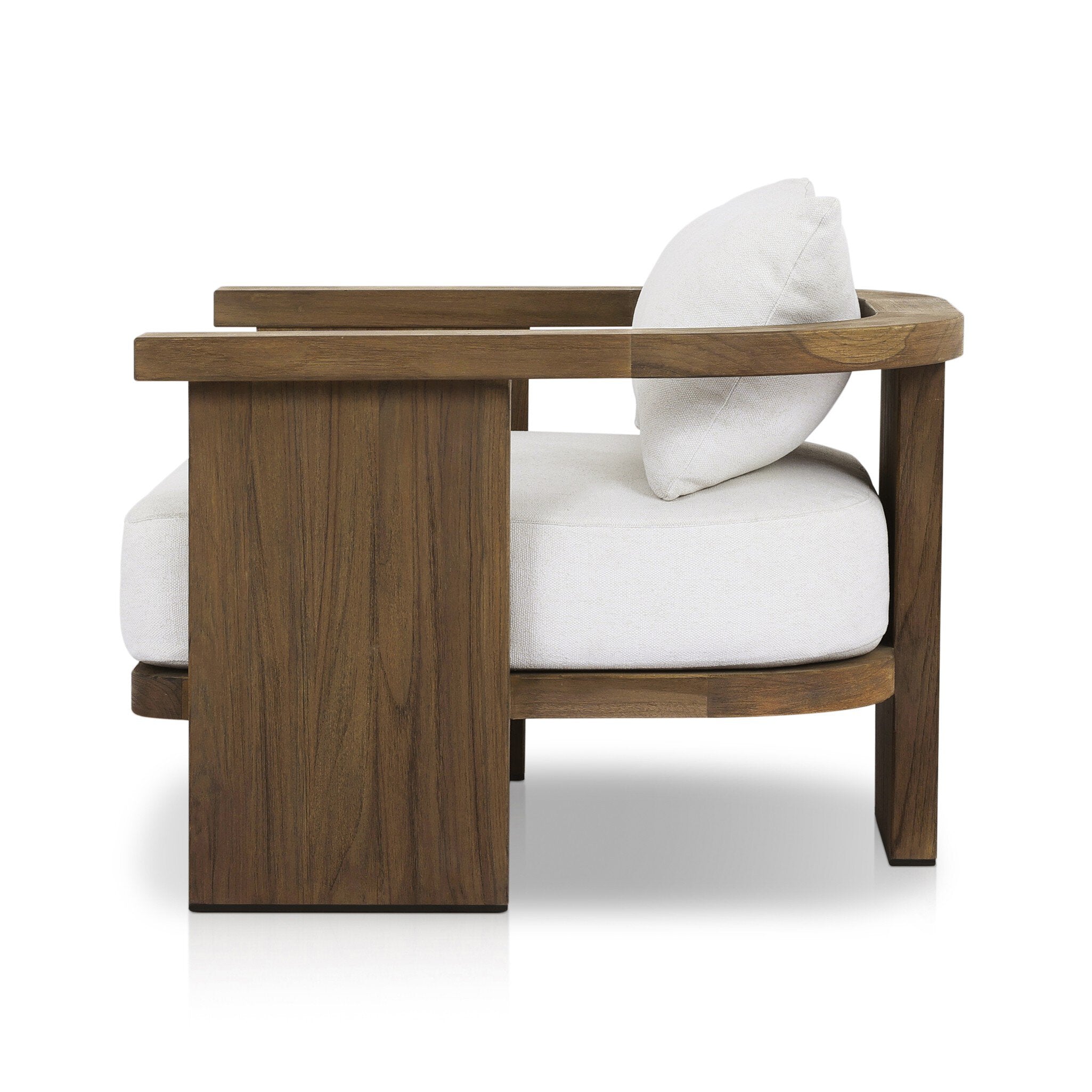 Side profile of an outdoor armchair with a curved wooden frame out of teak and white linen cushions on a white background.