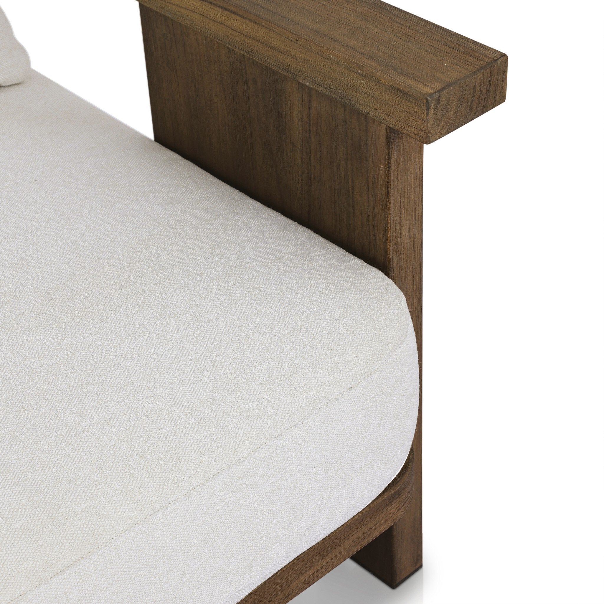 Close up view of an outdoor armchair with a curved wooden frame out of teak and white linen cushions on a white background.