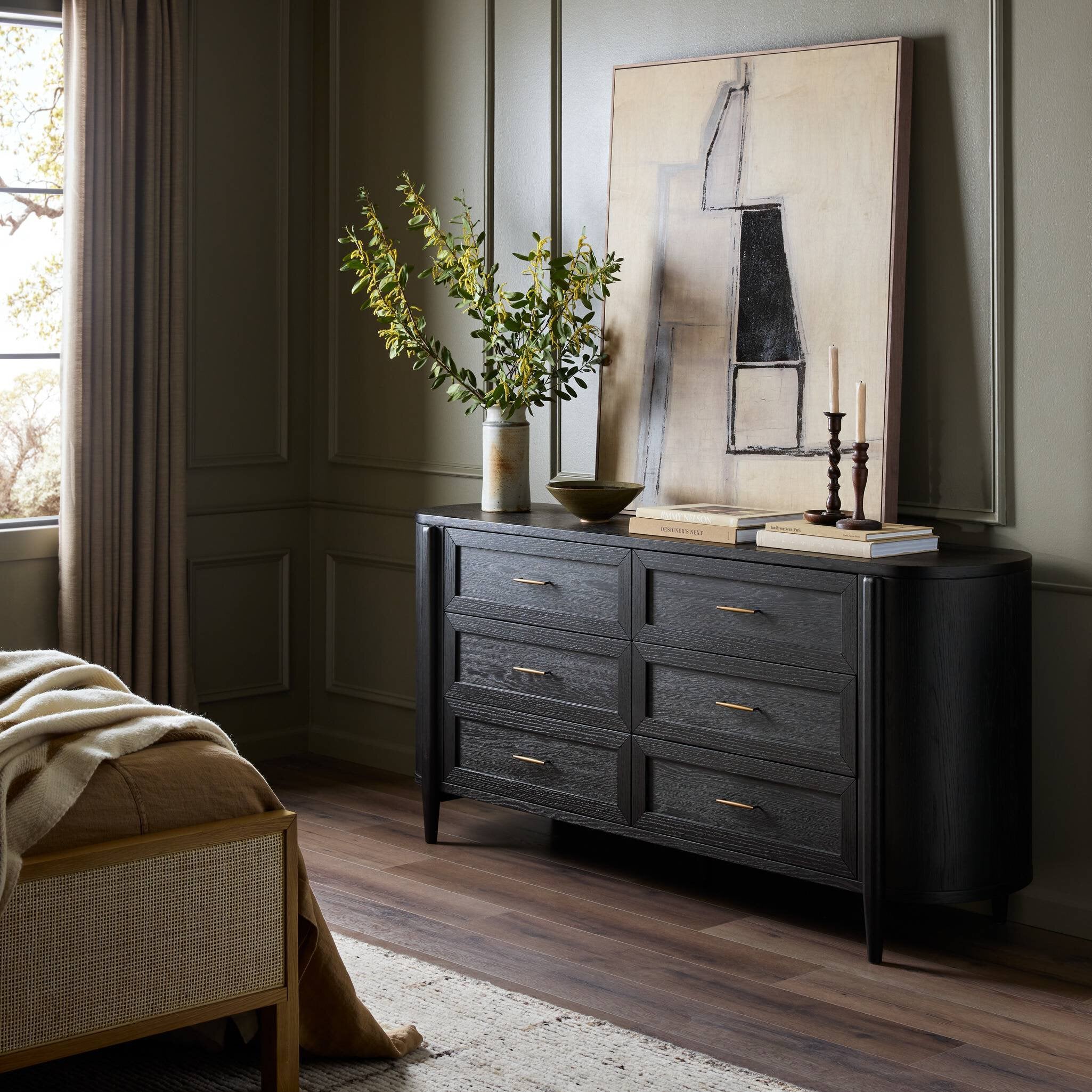 Dark wooden dresser in a room with a painting and plants on top. | Wildwood Home Co.
