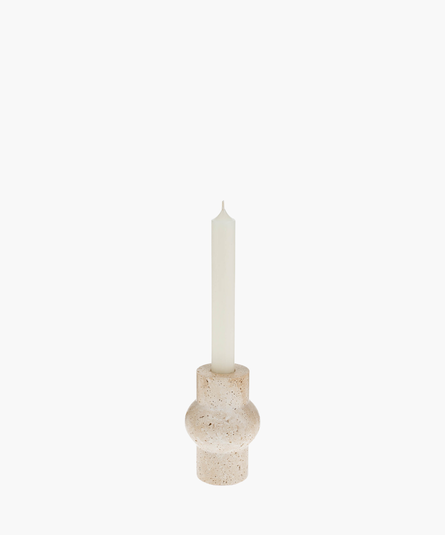 A tall white candle in a rounded, beige travertine stone holder with a textured surface. The minimalist design evokes a calm and serene atmosphere.
