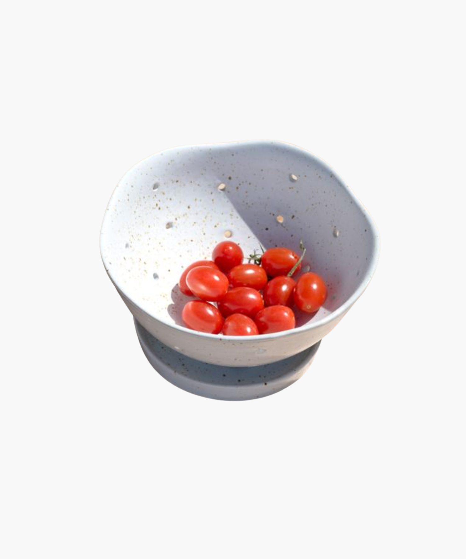 A white speckled ceramic bowl with drainage holes holds several vibrant red cherry tomatoes, creating a fresh and rustic tone. | Wildwood Home Co.