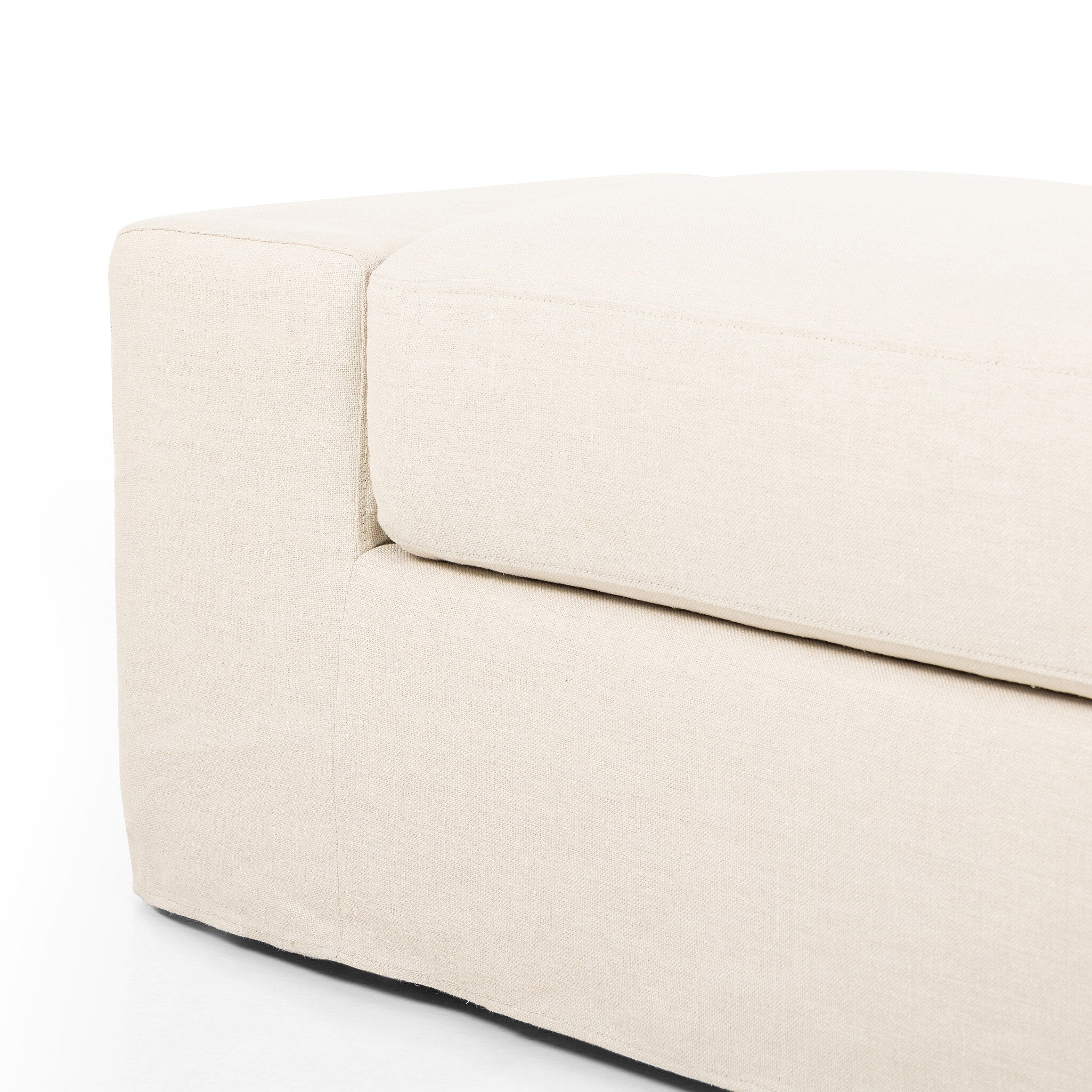 Close up of Ivory wide arm slipcover accent bench on a white background.