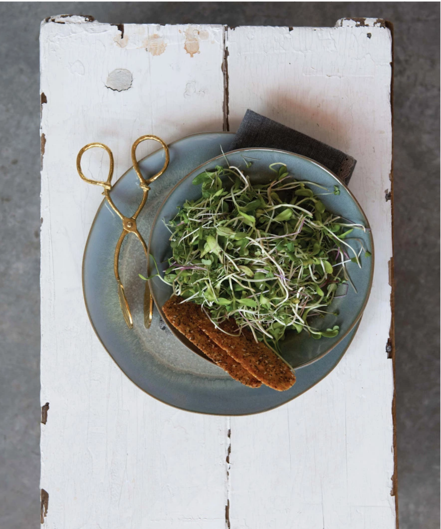 A pair of ornate, antique inspired gold tongs with detailed leaf engravings on the grips styled with a mixed greens salad. The design conveys elegance and vintage charm. | Wildwood Home Co.