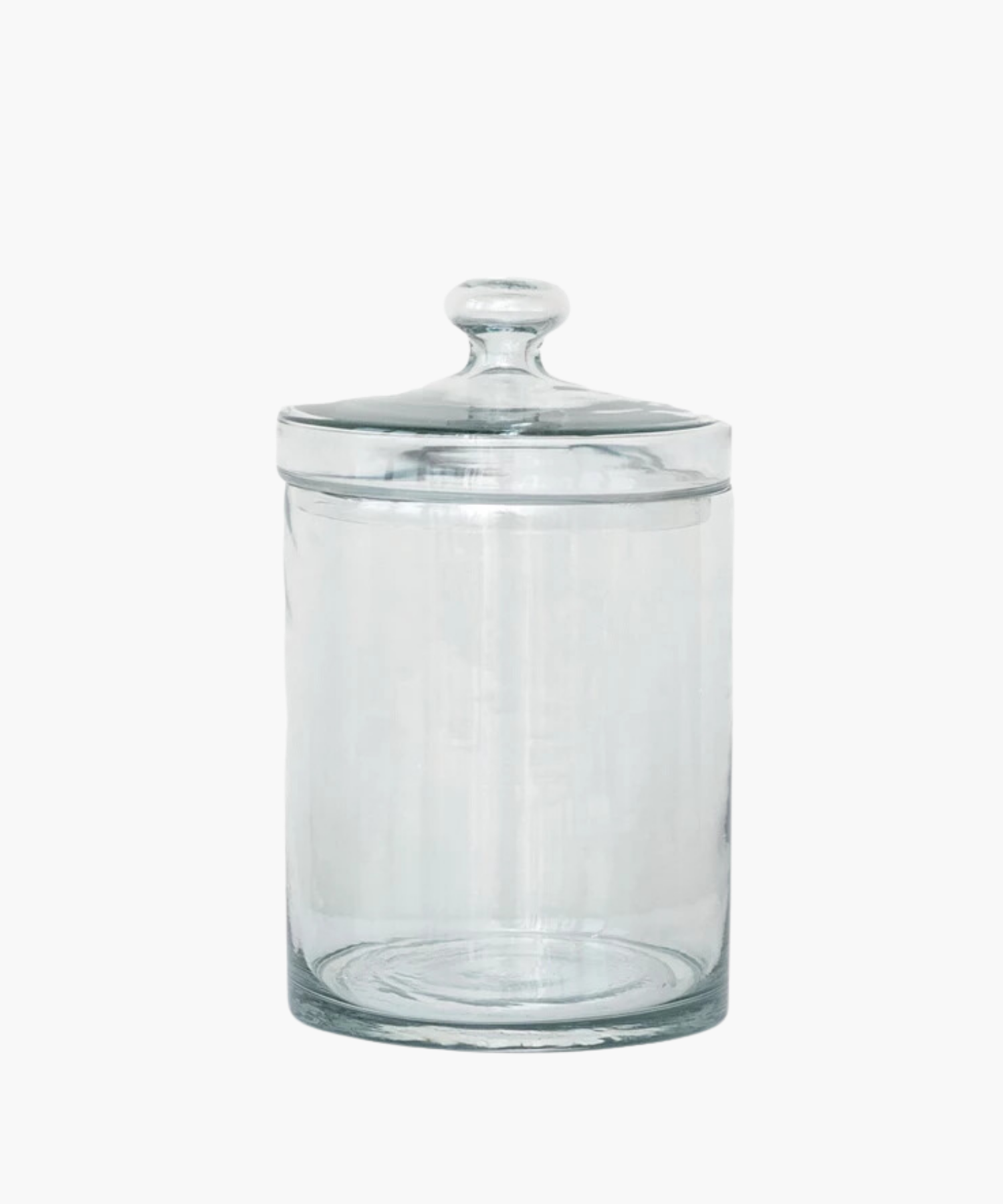 A transparent glass jar with a rounded lid is centered on a white background. The jar is empty and reflects light softly, conveying simplicity and elegance. | Wildwood Home Co.