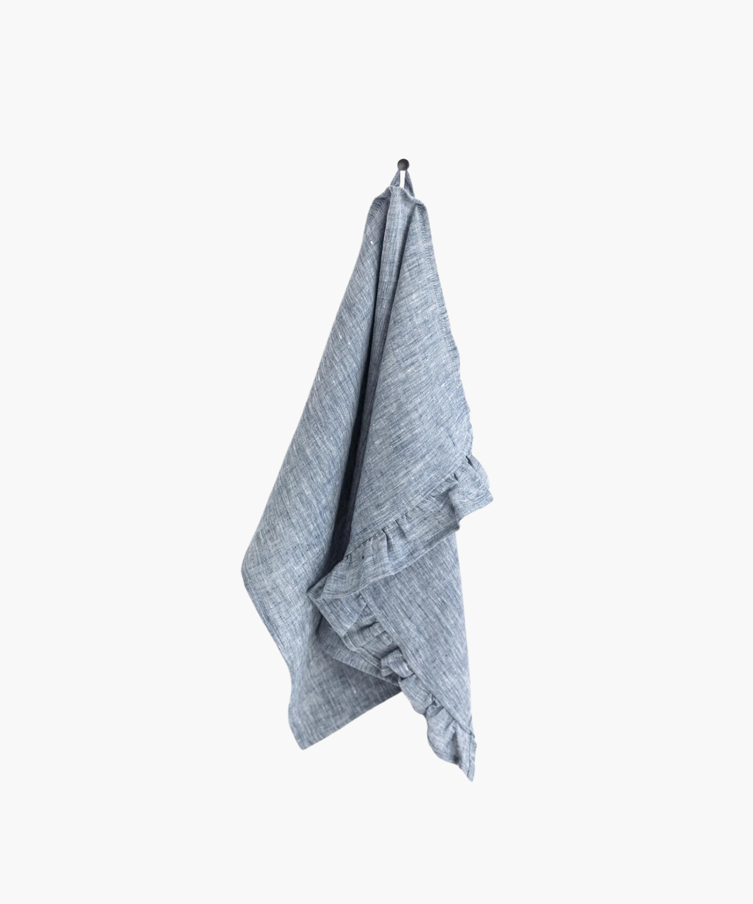 A blue linen tea towel with ruffle trim hangs neatly on a black hook against a plain white background, creating a clean and minimalistic appearance. | Wildwood Home Co.