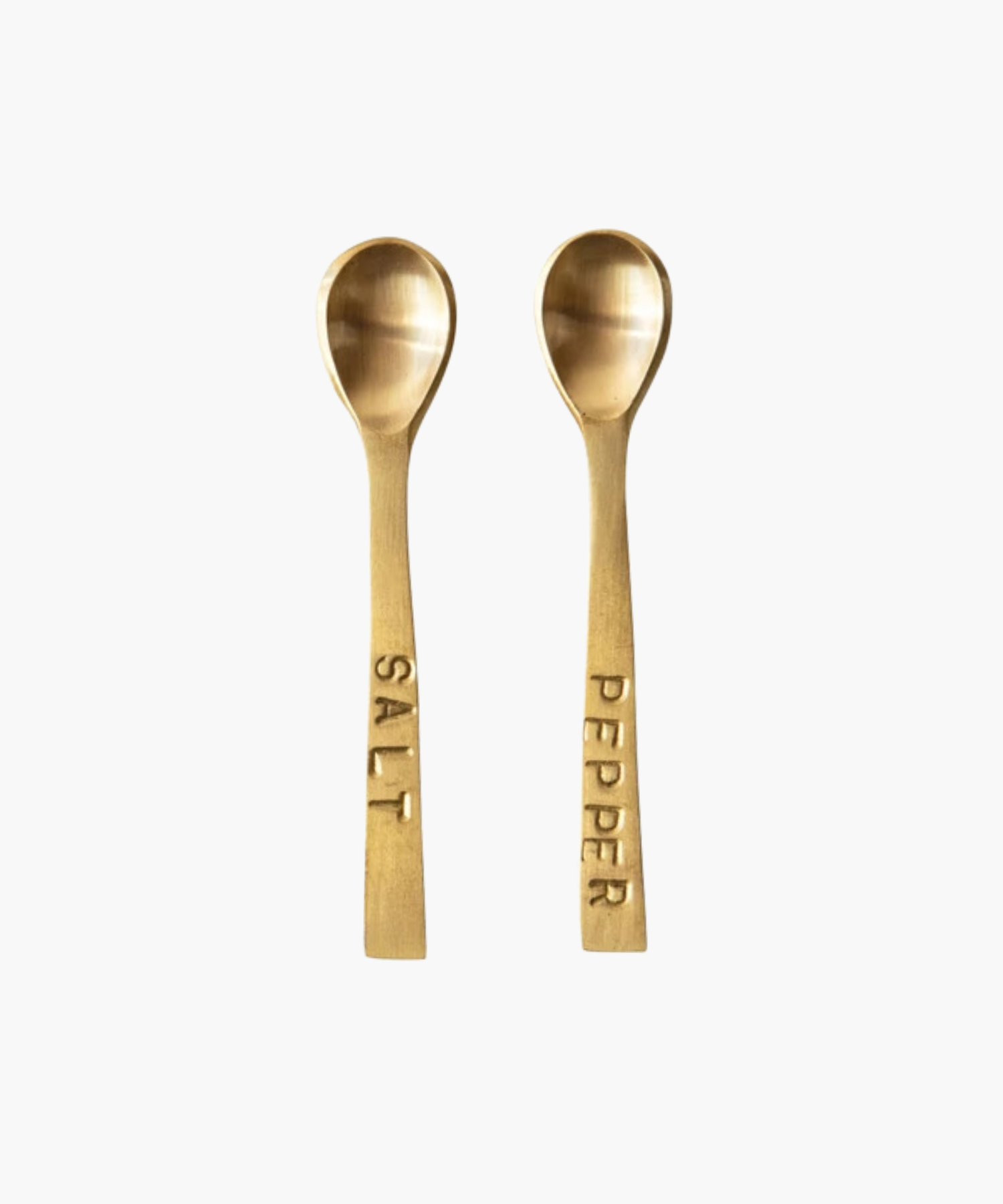 Two small elegant gold-toned spoons with engraved labels, "SALT" and "PEPPER," on their handles, set against a white background, conveying sophistication. | Wildwood Home Co.