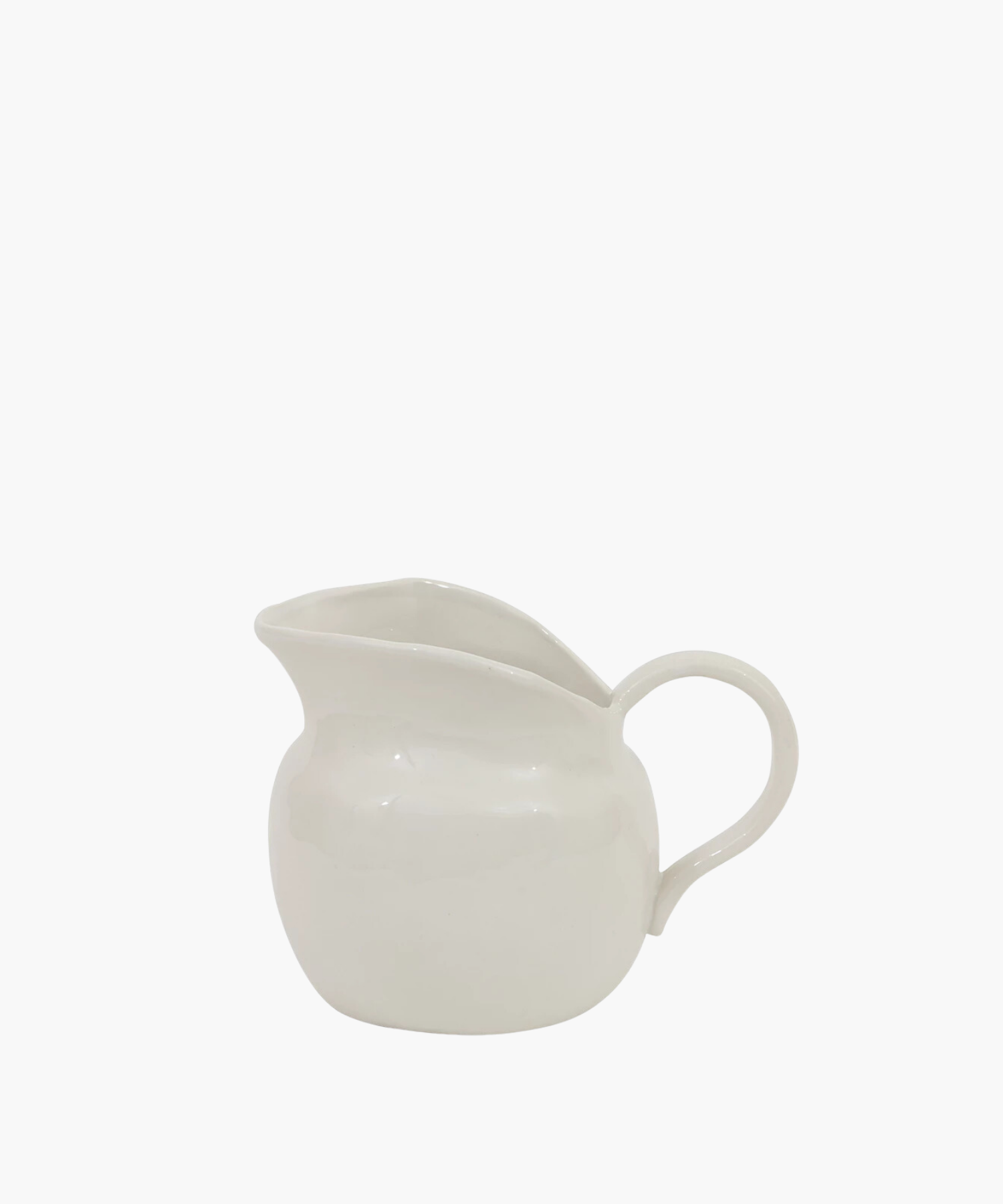White ceramic pitcher with a round base and a wide spout, featuring a smooth surface and a curved handle. The mood is minimalistic and elegant. | Wildwood Home Co.
